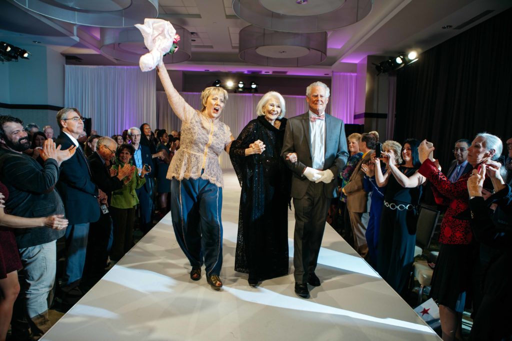 Triumphant as survivors on the runway! Sue Miller and I at the Sue Miller Day of Caring fashion show 2016. Photo by Hardy Klahold.