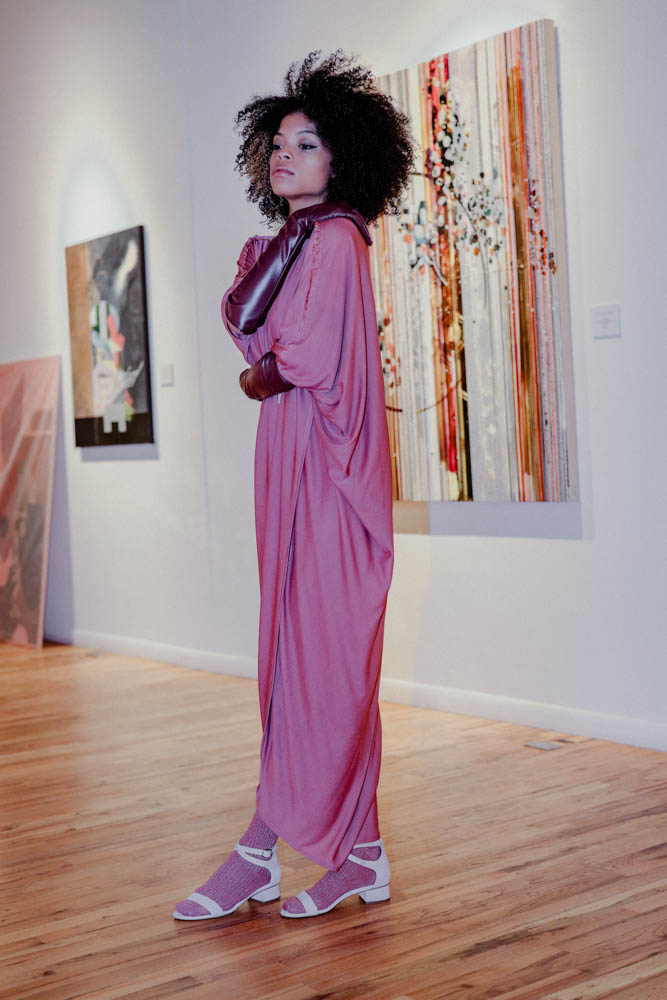 DanShay in a draped jersey dress in front of art by Nina Tichava.